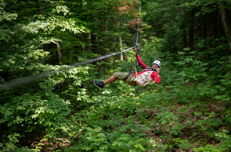 Guest soaring on a giant zipline at Treetop Trekking Huntsville, surrounded by towering forests and Canadian Shield landscapes in Muskoka